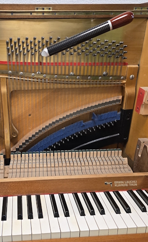 Offenes Klavier mit Tastatur, Saiten und Stimmwirbel mit Stimmschlüssel.