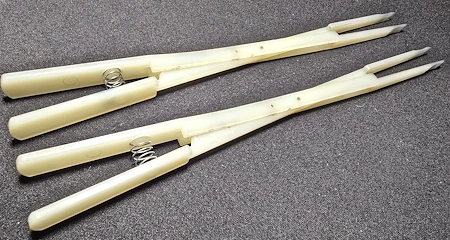 Zwei Diskant-Stimmkeile aus Nylon mit Federn auf schwarzer Unterlage.
