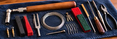 Stimmwerkzeuge für Klaviere und Flügel auf einem blauen Tuch ausgelegt: Stimmhammer, Stimmgabel, Stimmkeile, Ersatzsaiten und weiteres Spezialwerkzeug